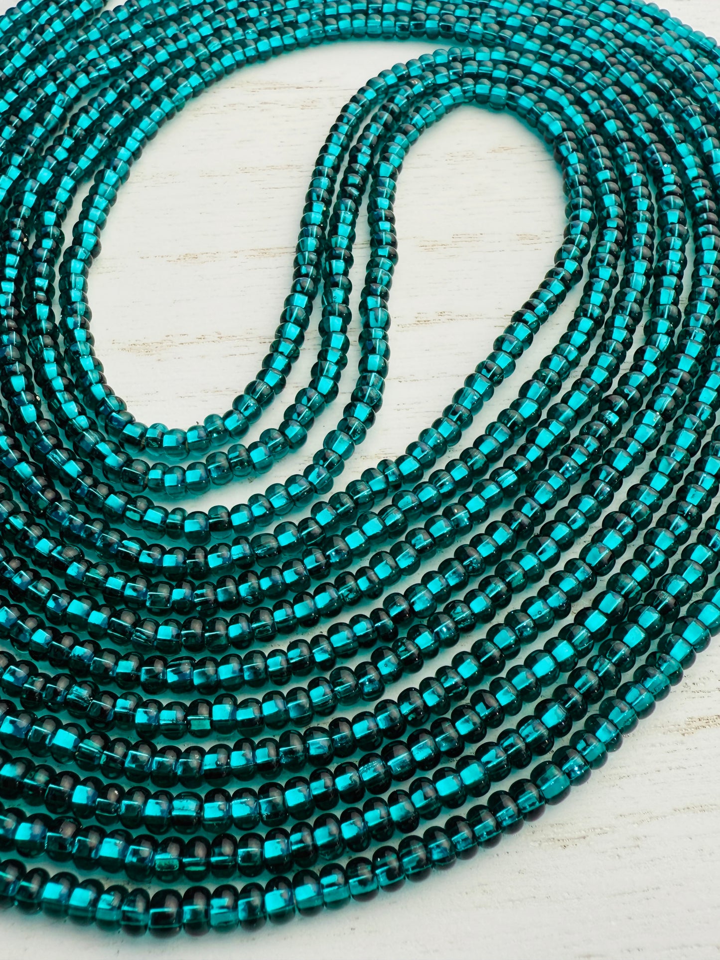 Emerald green glass waist beads on a light wooden surface