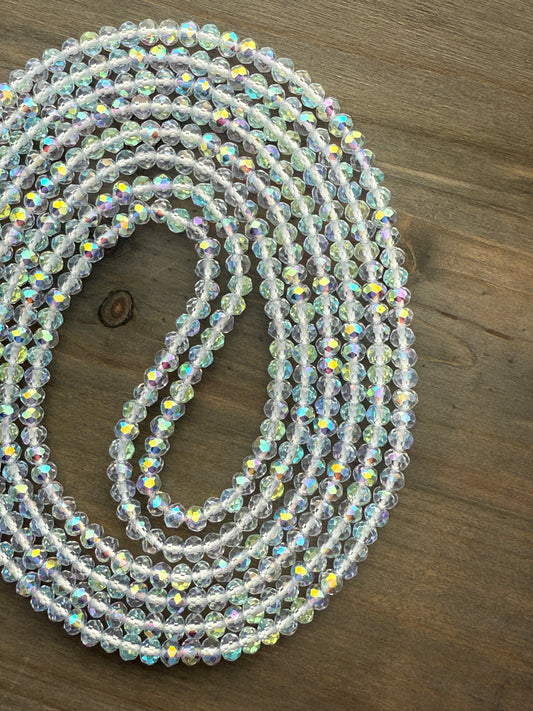 Coiled string of clear baby crystal waist beads on a wooden surface
