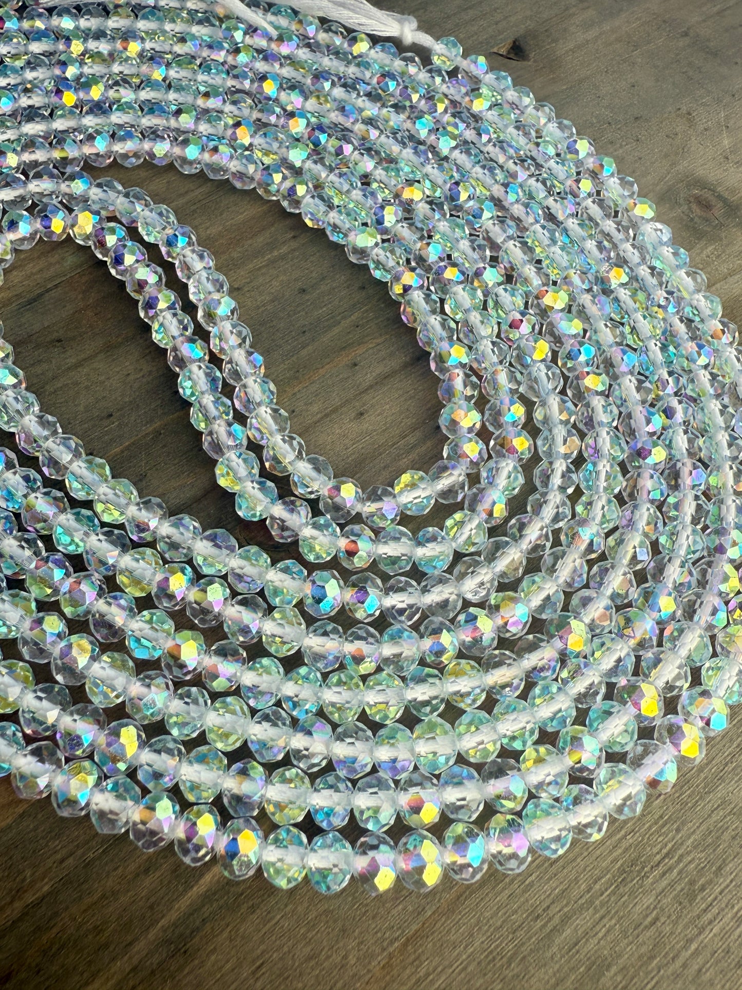 Coiled string of clear baby crystal waist beads on a wooden surface