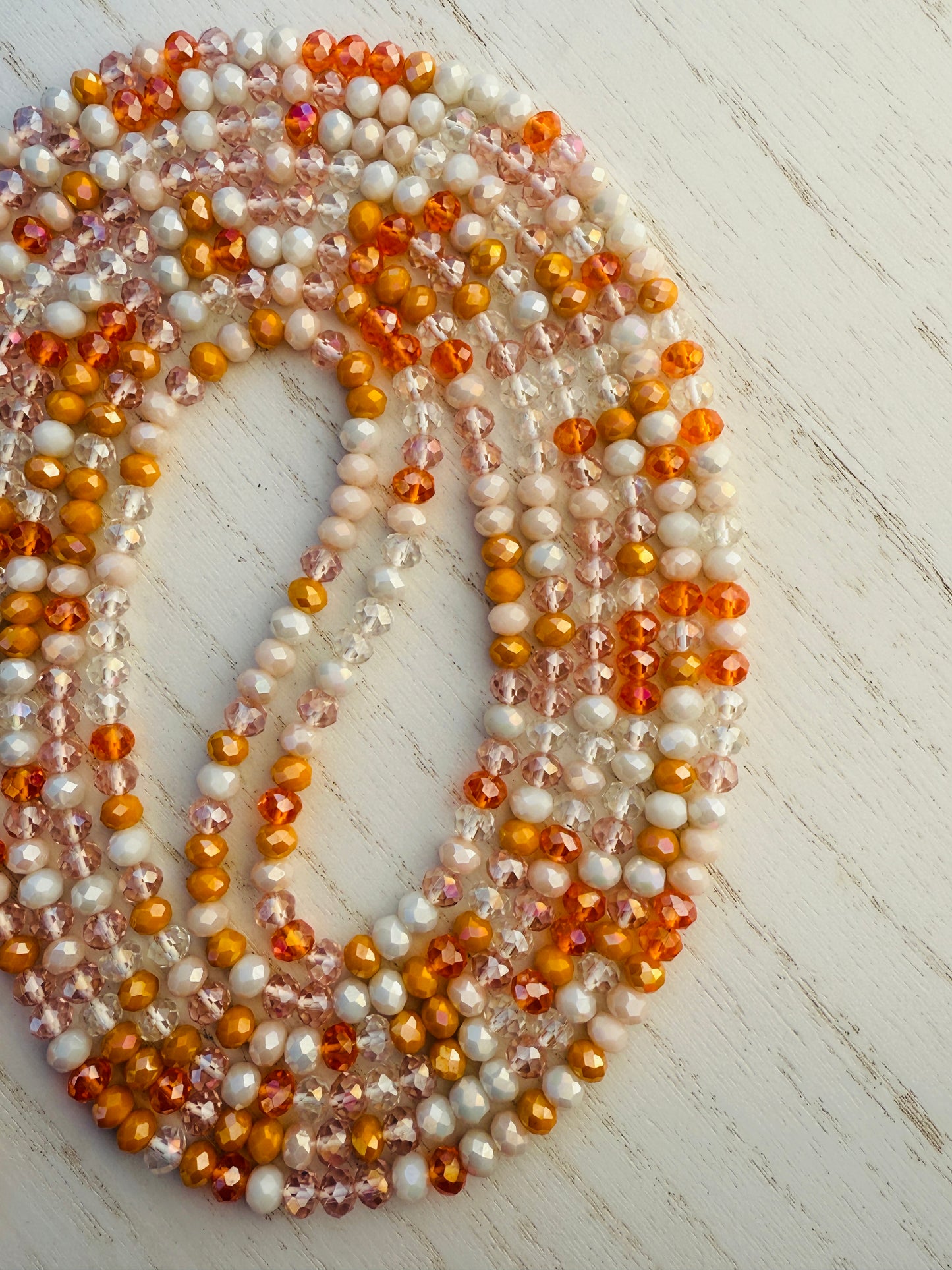 Multicolor orange waist bead on a light wooden surface