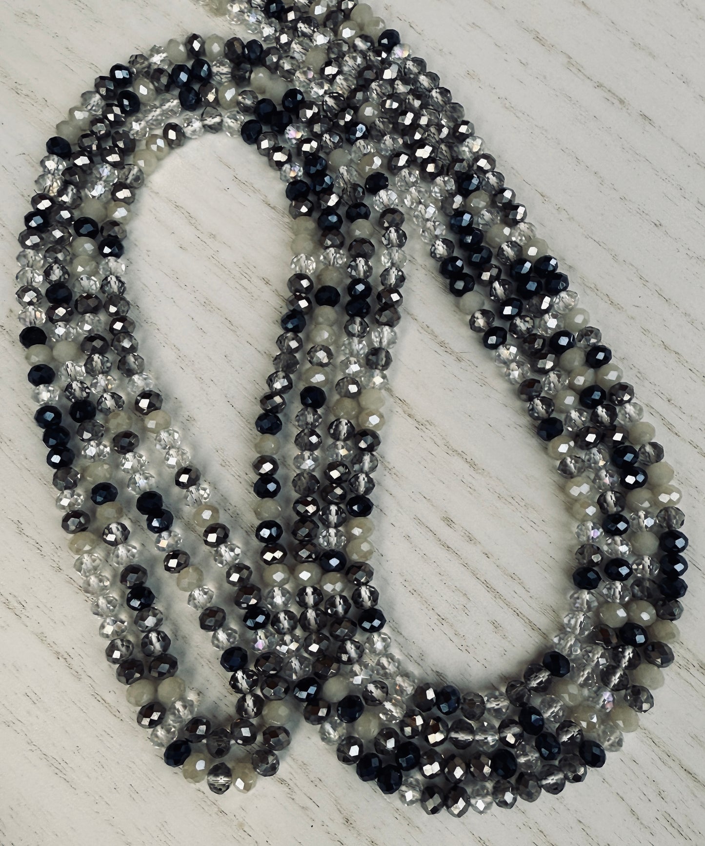 black, clear, and gray faceted crystal waist beads styled in a circular pattern on a light surface