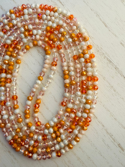 Multicolor orange waist bead on a light wooden surface