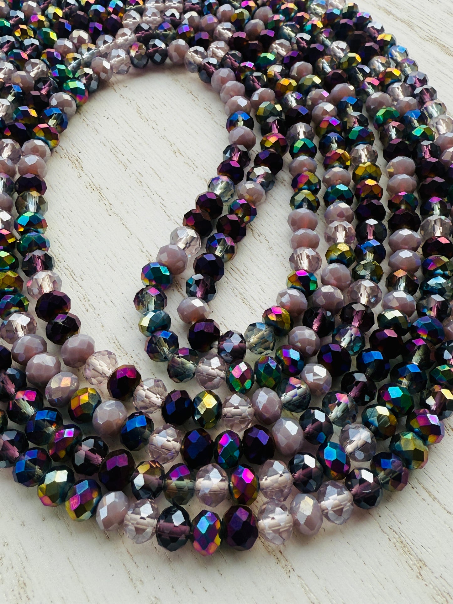 iridescent purple and lavender crystal waist beads arranged in a circular display on a light background