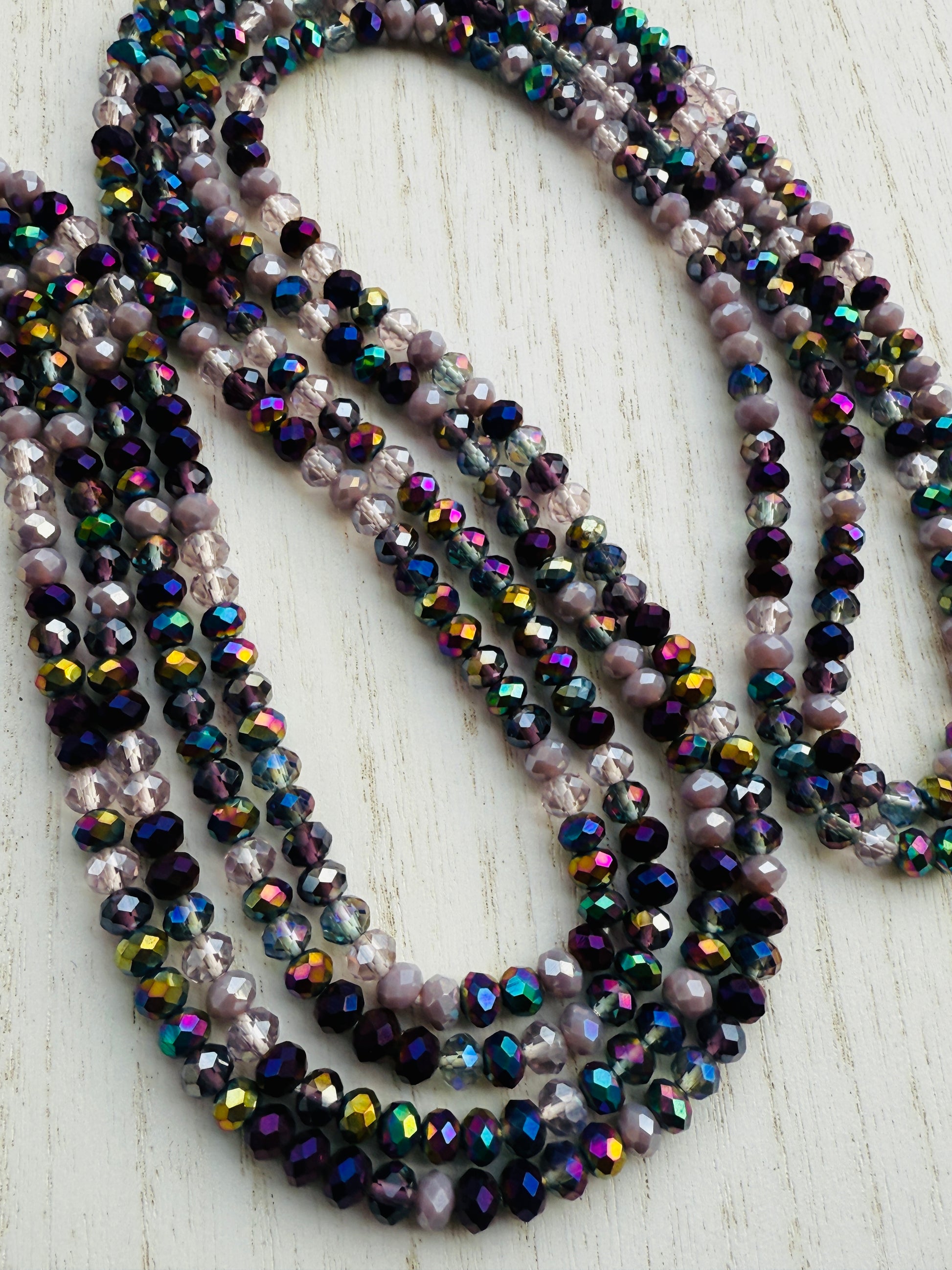 iridescent purple and lavender crystal waist beads arranged in a circular display on a light background