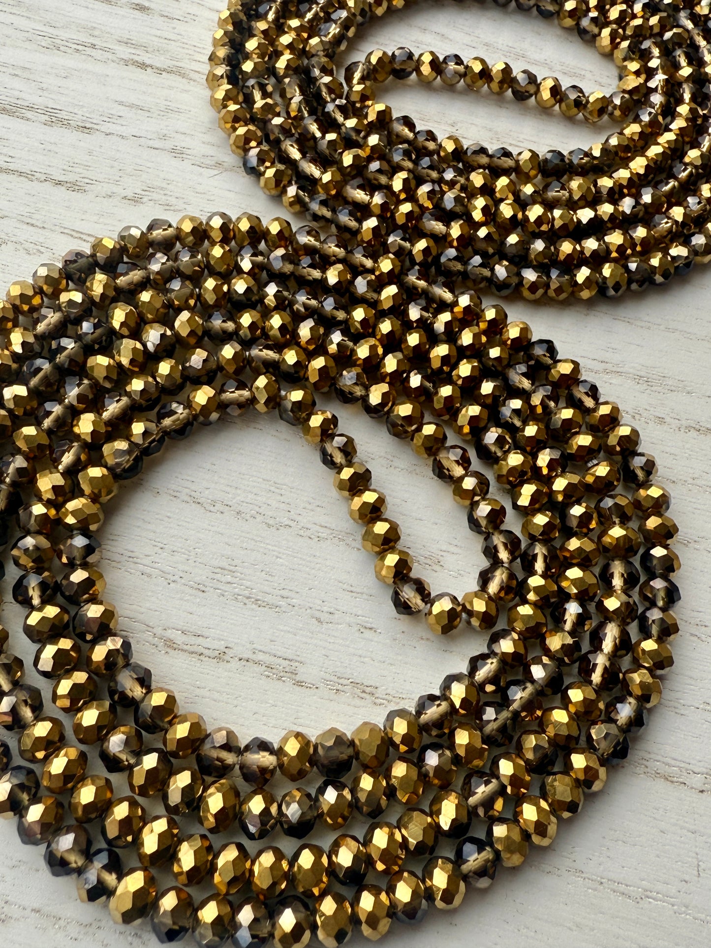 gold and bronze faceted crystal waist beads displayed in a circle on a neutral textured surface
