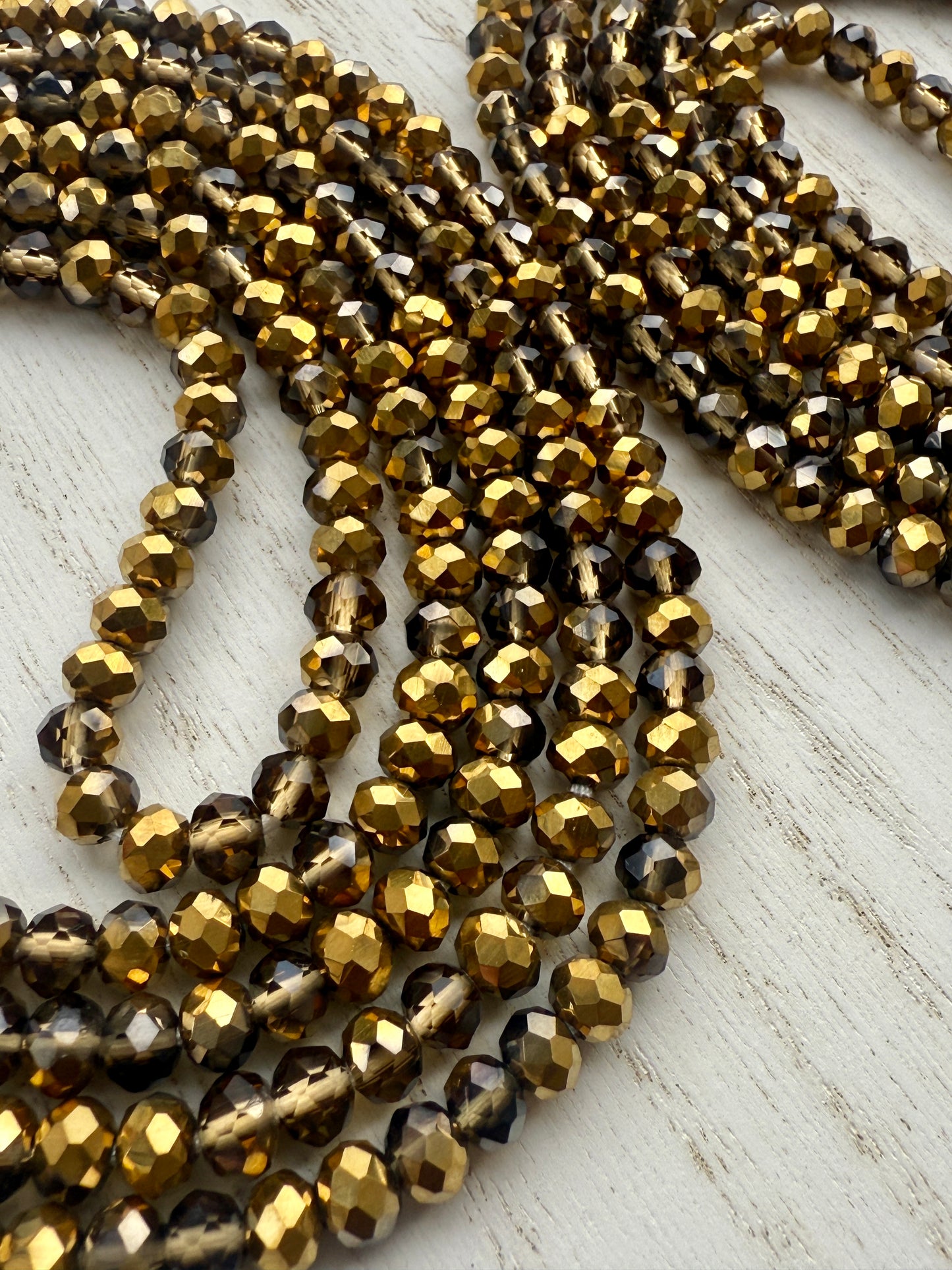 gold and bronze faceted crystal waist beads displayed in a circle on a neutral textured surface