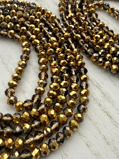 gold and bronze faceted crystal waist beads displayed in a circle on a neutral textured surface