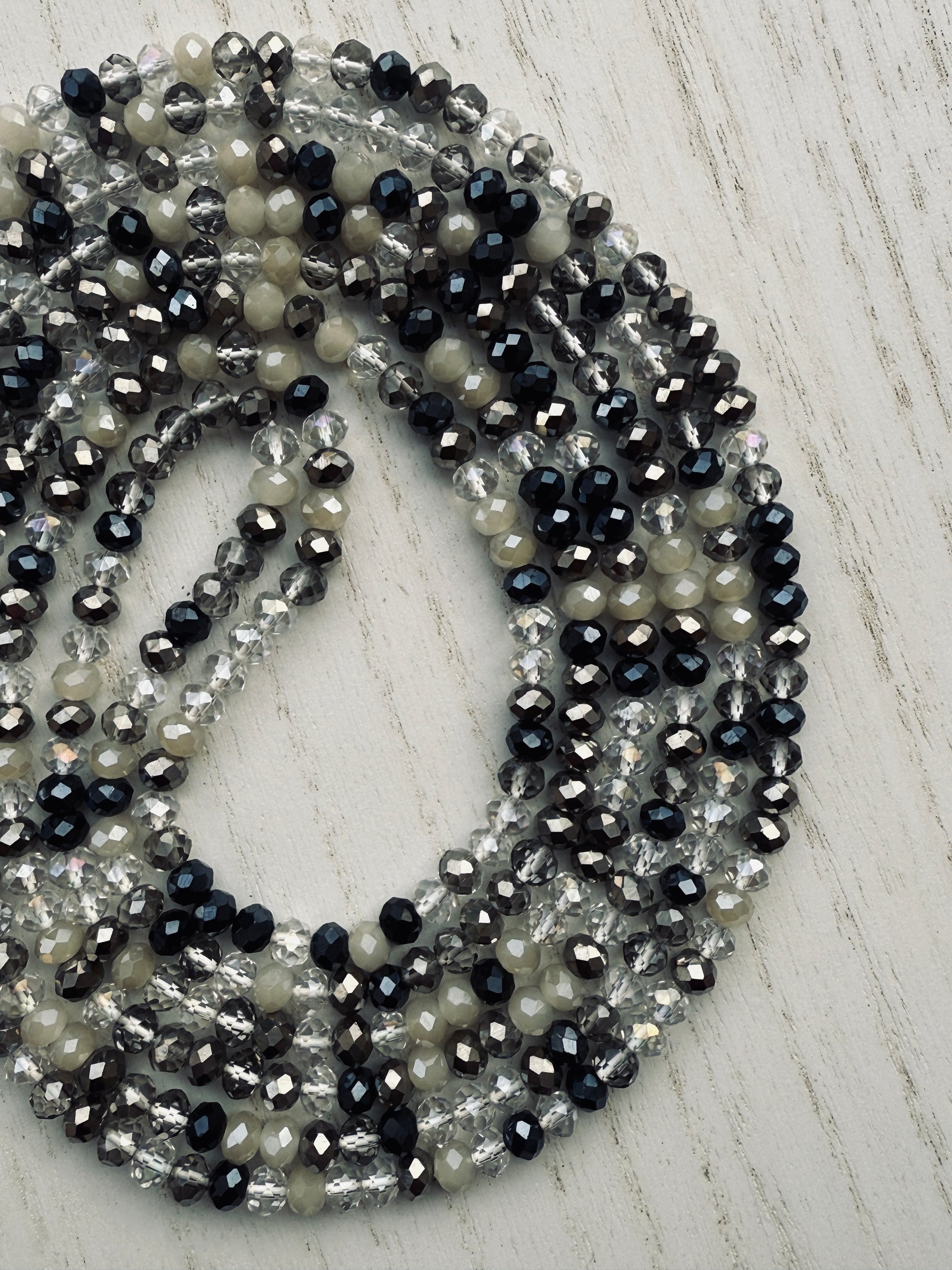 black, clear, and gray faceted crystal waist beads styled in a circular pattern on a light surface