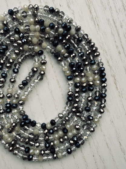 black, clear, and gray faceted crystal waist beads styled in a circular pattern on a light surface