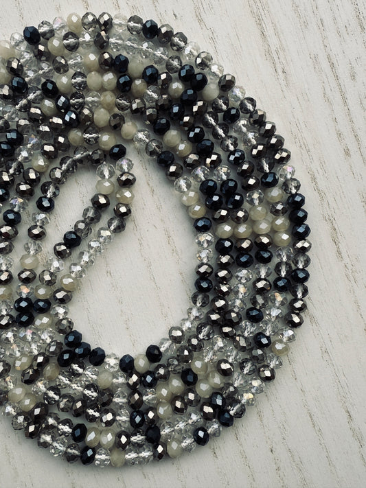 black, clear, and gray faceted crystal waist beads styled in a circular pattern on a light surface