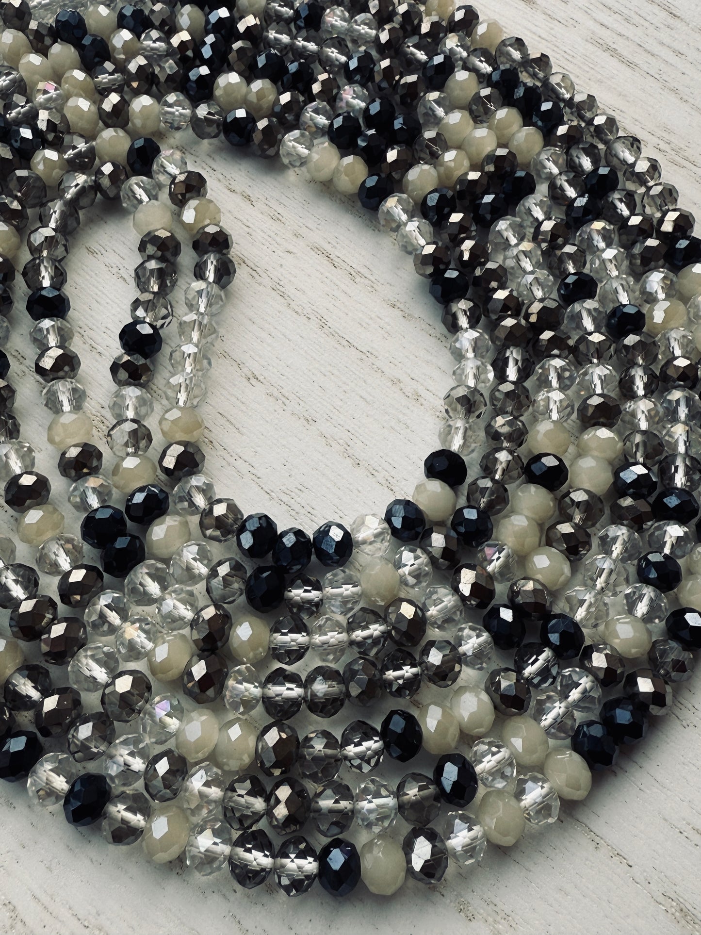 black, clear, and gray faceted crystal waist beads styled in a circular pattern on a light surface
