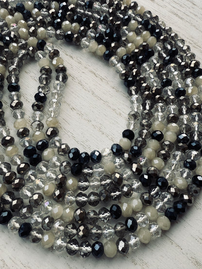 black, clear, and gray faceted crystal waist beads styled in a circular pattern on a light surface