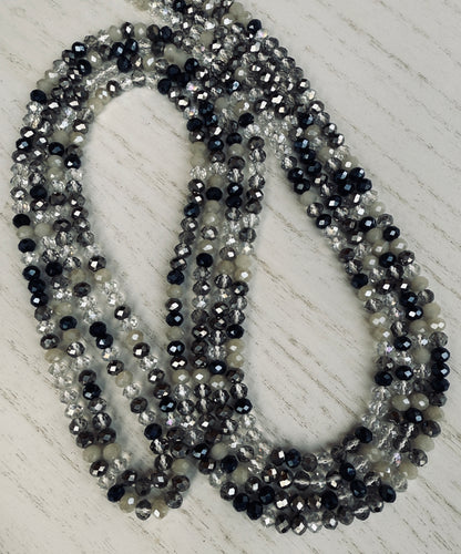 black, clear, and gray faceted crystal waist beads styled in a circular pattern on a light surface