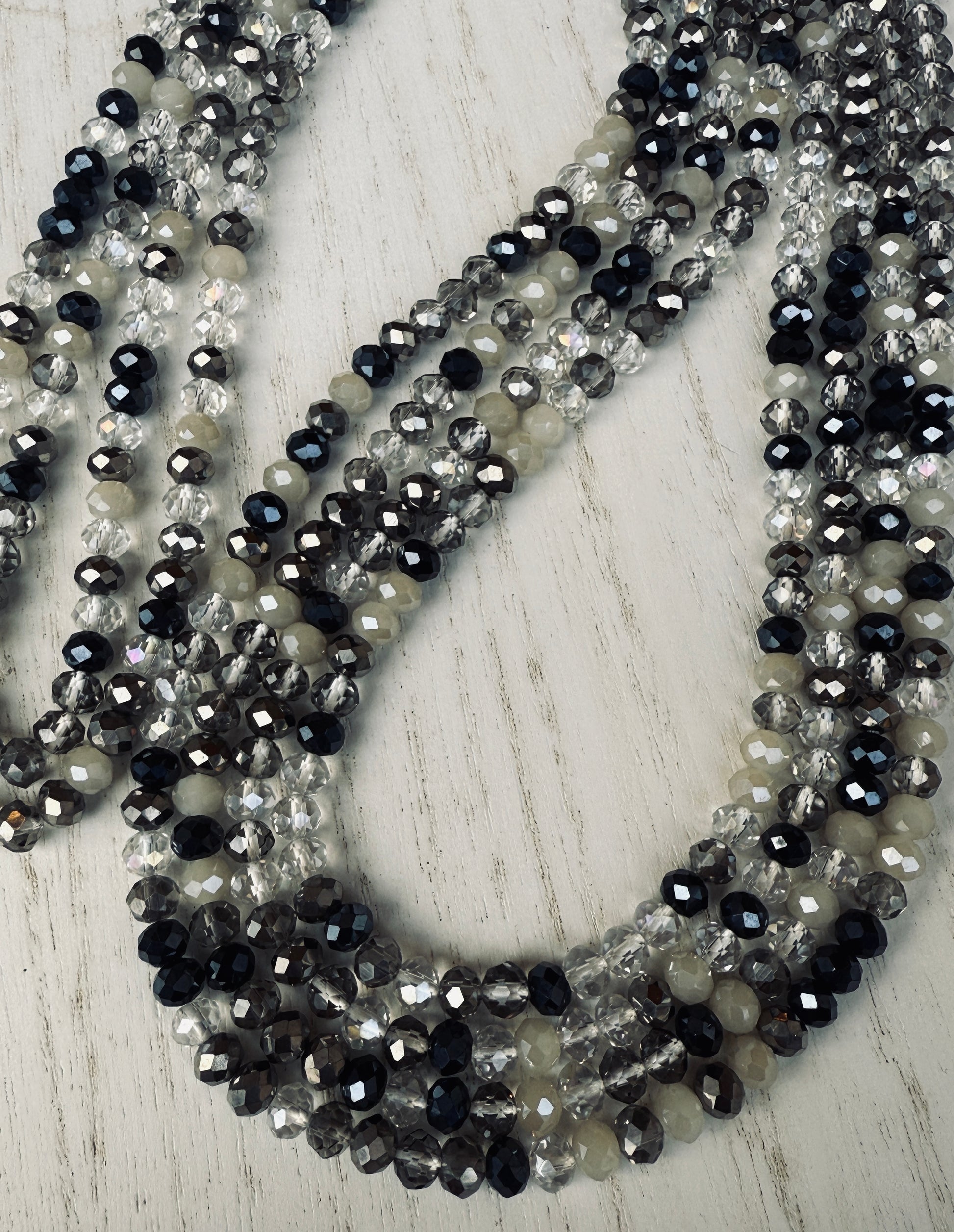 black, clear, and gray faceted crystal waist beads styled in a circular pattern on a light surface