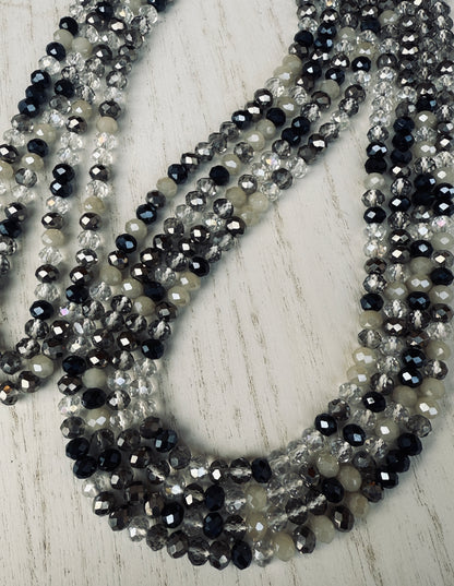 black, clear, and gray faceted crystal waist beads styled in a circular pattern on a light surface