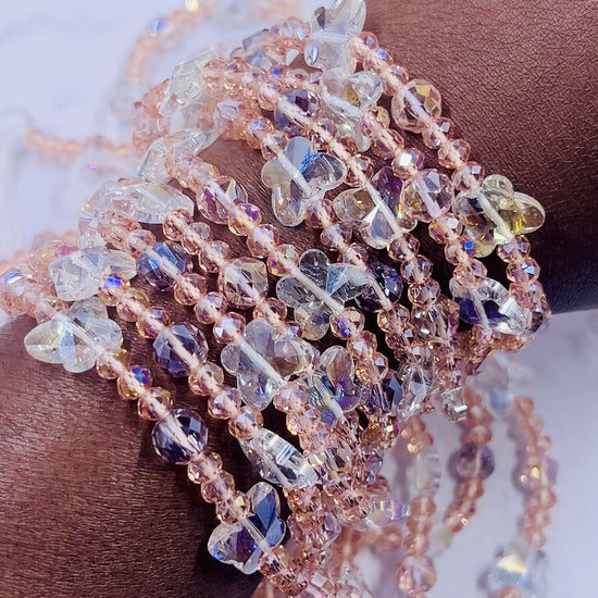 Rose gold waist beads with faceted beads and clear gemstones, coiled neatly on a white surface.