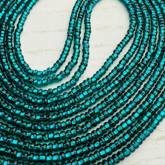 Emerald green glass waist beads on a light wooden surface