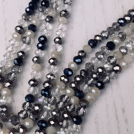 black, clear, and gray faceted crystal waist beads styled in a circular pattern on a light surface