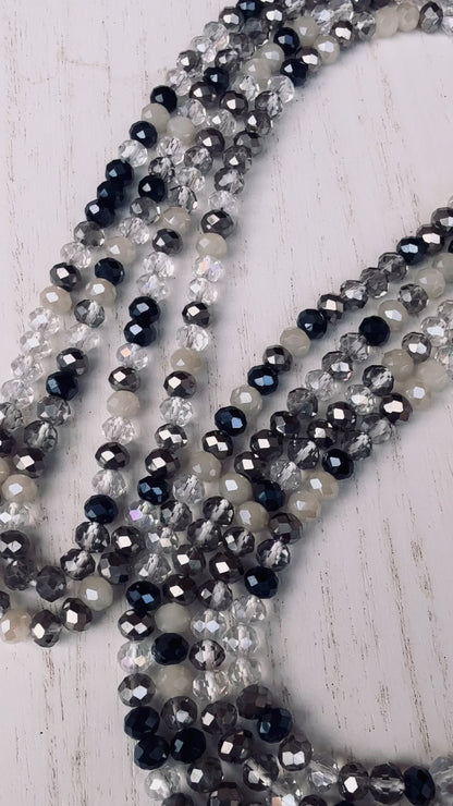black, clear, and gray faceted crystal waist beads styled in a circular pattern on a light surface
