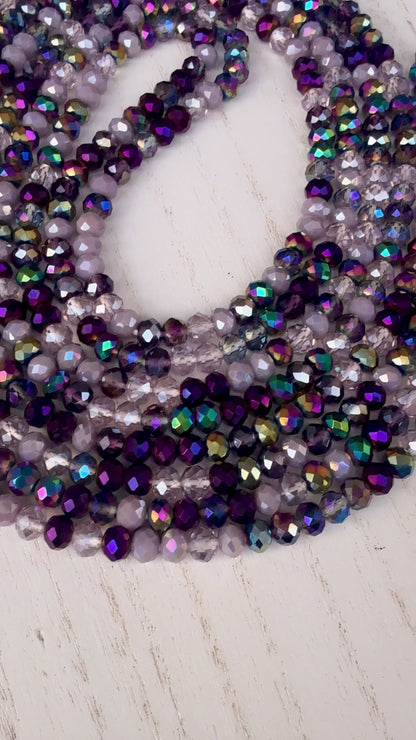iridescent purple and lavender crystal waist beads arranged in a circular display on a light background