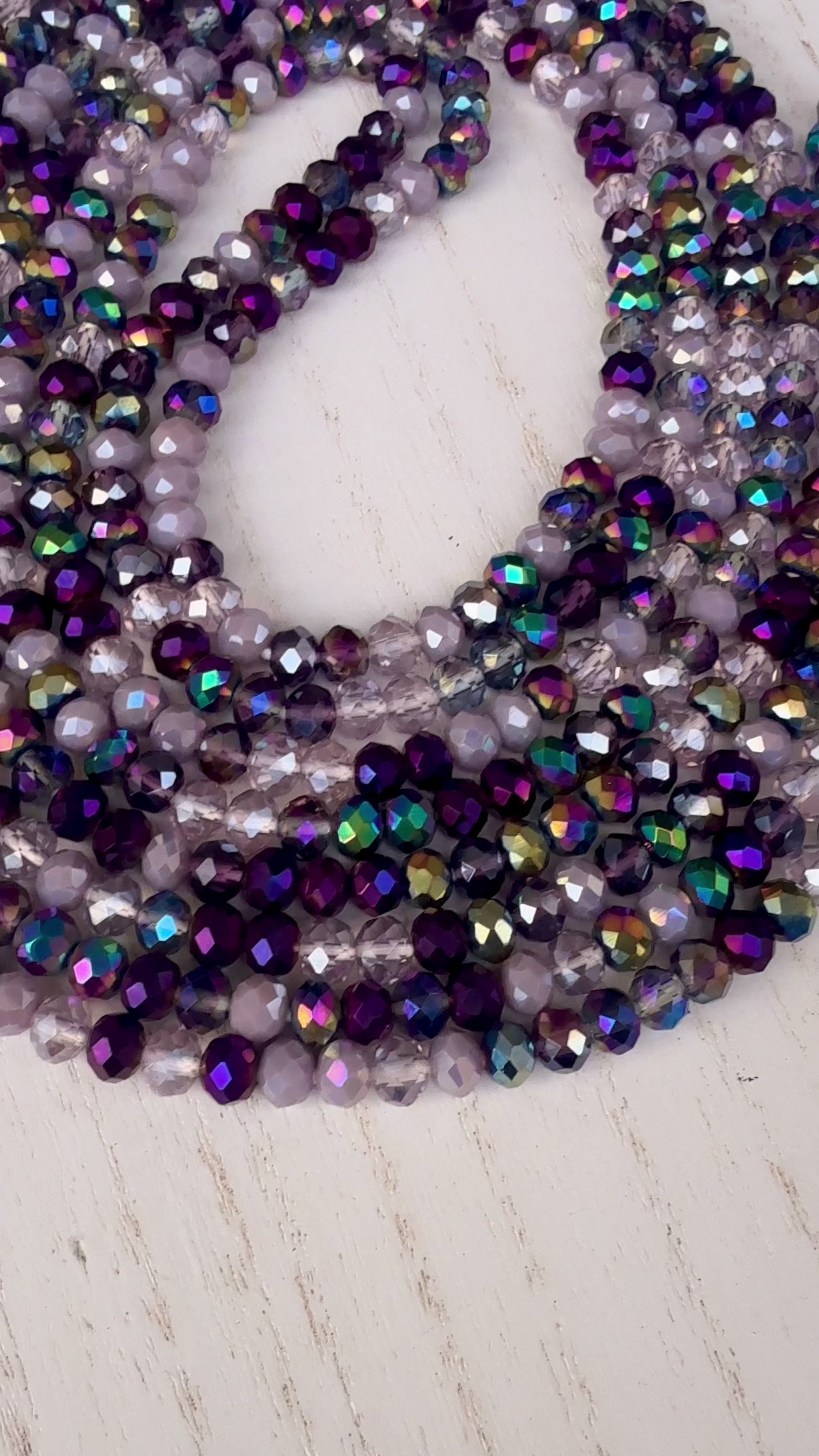 iridescent purple and lavender crystal waist beads arranged in a circular display on a light background
