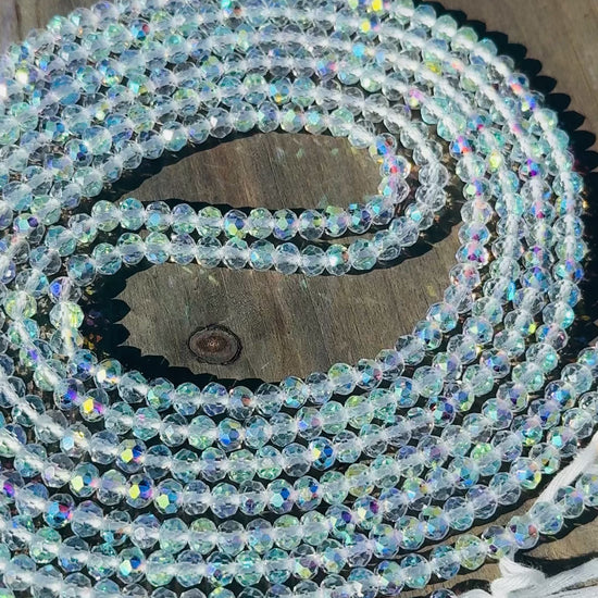 Coiled string of clear baby crystal waist beads on a wooden surface