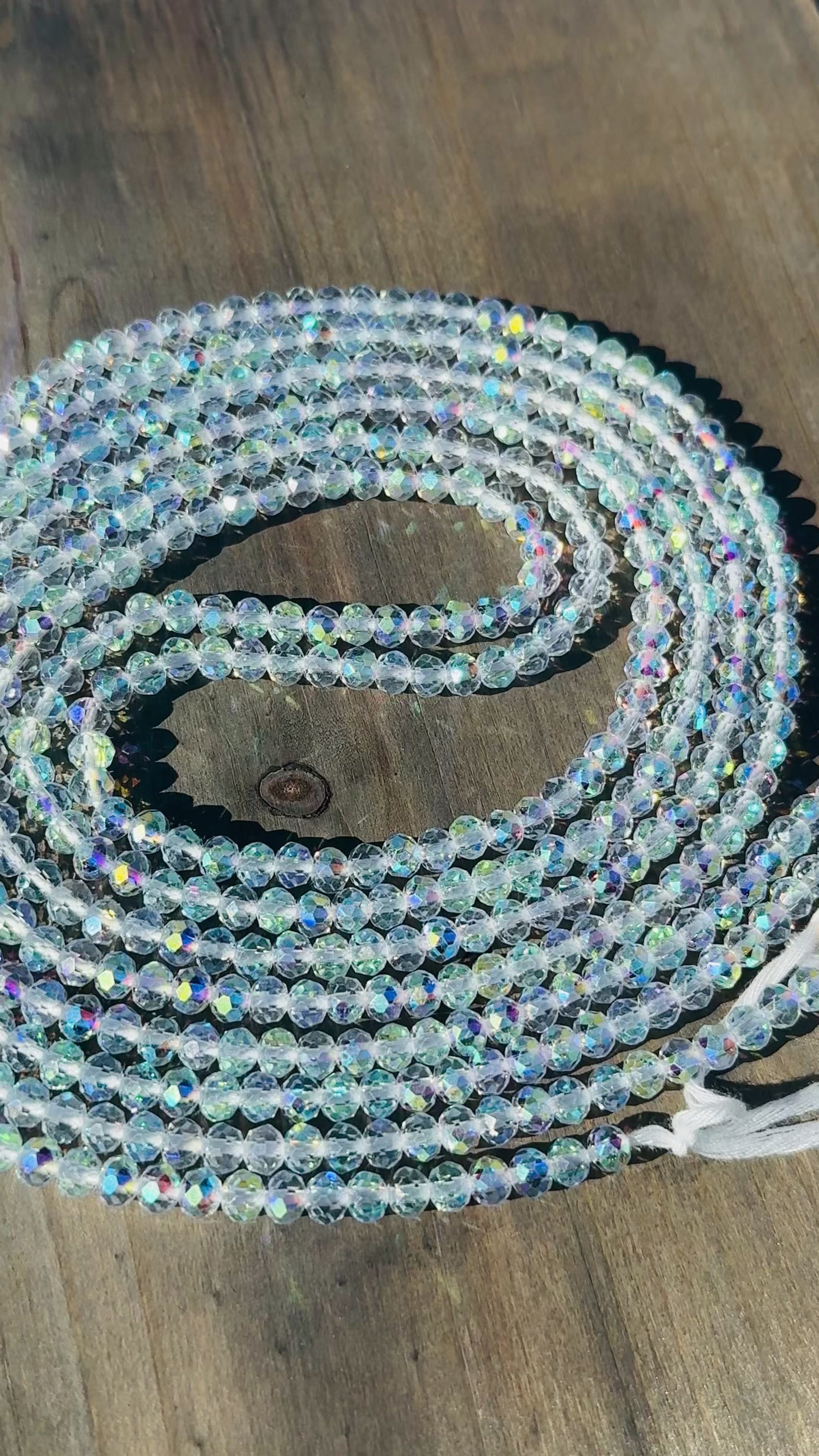 Coiled string of clear baby crystal waist beads on a wooden surface
