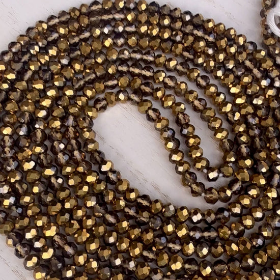 gold and bronze faceted crystal waist beads displayed in a circle on a neutral textured surface